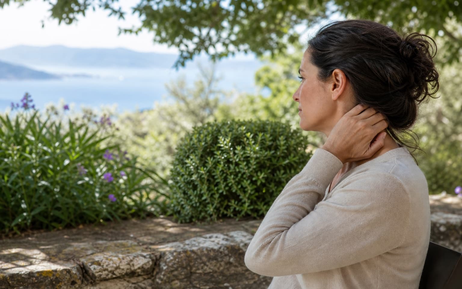 Femme touchant doucement le haut de sa nuque dans un jardin méditerranéen à Ajaccio